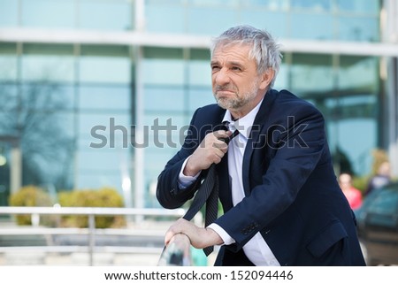 Depressed businessman. Depressed senior man in formalwear holding hand in hair and looking away