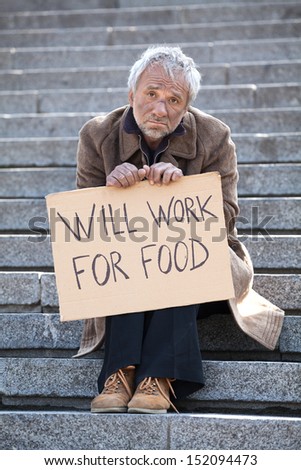 Will work for food. Depressed man in dirty wear sitting on stairs and holding poster