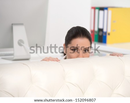 Businesswoman hiding. Frustrated middle-aged businesswoman looking out of the couch
