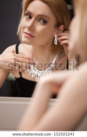 Beautiful mature woman. Beautiful middle aged woman putting on the earrings