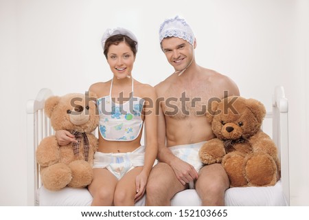 Big babies. Two infant young people in baby wear and diapers holding teddy bears and smiling
