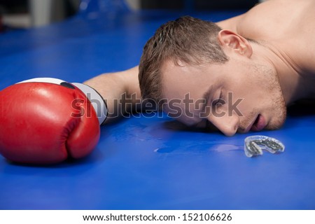 Defeated boxer. Close-up of defeated boxer lying down on the boxing ring with closed eyes