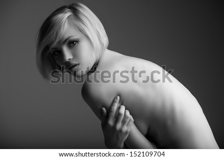 Naked beauty. Black and white side view image of beautiful naked woman bending and looking at camera