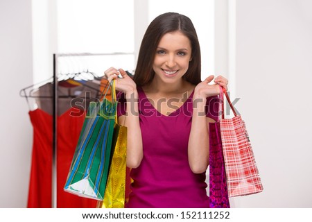 Woman at the retail store. Cheerful young woman holding shopping bags and smiling