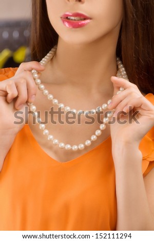 Pearl necklace. Cropped image of beautiful young woman putting on pearl necklace