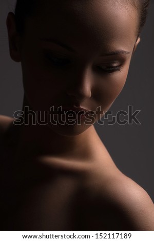 Beauty in the dark. Portrait of beautiful young naked woman looking away while isolated on grey