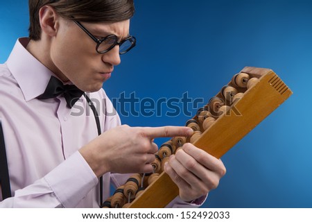 Nerd with abacus. Side view of young nerd man holding abacus and counting while isolated on blue