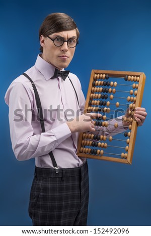 Nerd with abacus. Young nerd man holding abacus and pointing it while isolated on blue