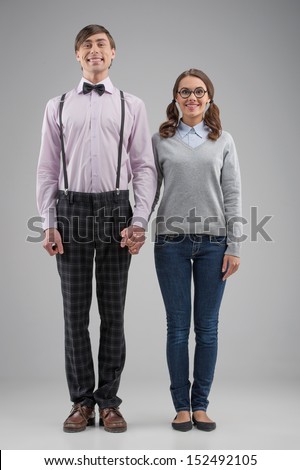 Nerd couple. Full length of happy nerd couple standing isolated on grey