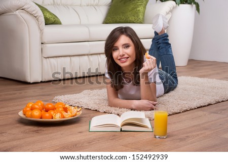 Woman relaxing at home. Beautiful young woman lying on the floor at home and reading book