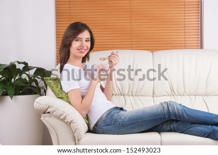 Woman eating dessert. Cheerful young woman sitting on the coach and eating dessert