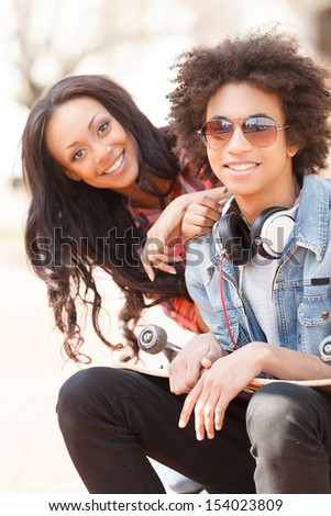 Teenage friends. Two cheerful teenage friends sitting close to each other and smiling at camera