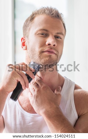 Man shaving. Handsome young man shaving with electric razor