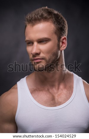 Handsome man. Portrait of handsome young man looking away while standing isolated on grey
