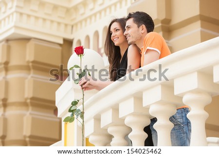 Loving couple. Low angle view of cheerful young couple standing close to each other and looking away