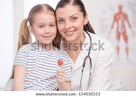 Doctor and little patient. Doctor and little girl with lollipop looking at camera and smiling
