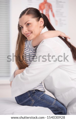 Doctor and little girl. Cheerful young doctor hugging her little patient