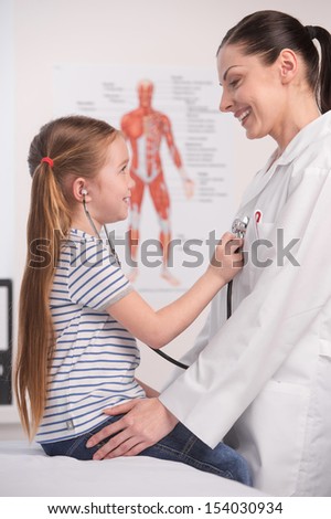 Doctor and little girl. Cheerful little girl examining doctor with stethoscope
