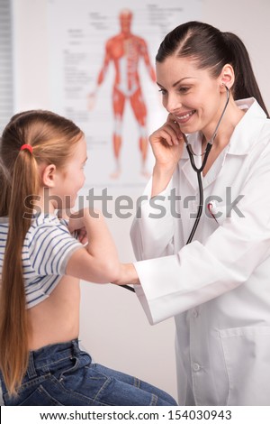Doctor and child. Cheerful young doctor in lab coat examining little girl