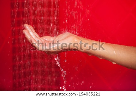 Falling water. Close-up of female hand under falling water