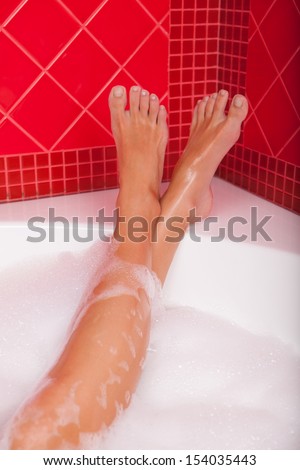 Legs in bubble bath. Close-up of beautiful female legs in bubble bath