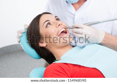 Patient at dentist office. Top view of beautiful young woman sitting at the chair in dental office and doctor examining teeth
