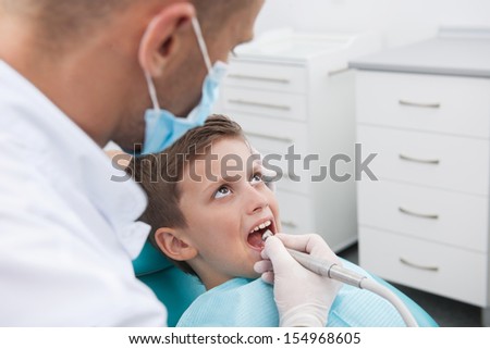 Little patient at dentist office. Top view of little boy sitting at the chair in dental office while doctor examining teeth