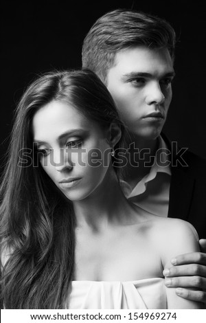 Depressed couple. Black and white image of sad young couple in formalwear standing close to each other and looking away