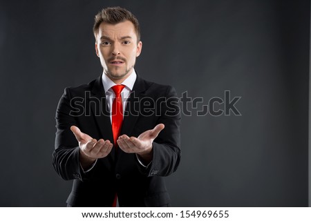 Businessman. Frustrated young men stretching out his hands while standing isolated on black
