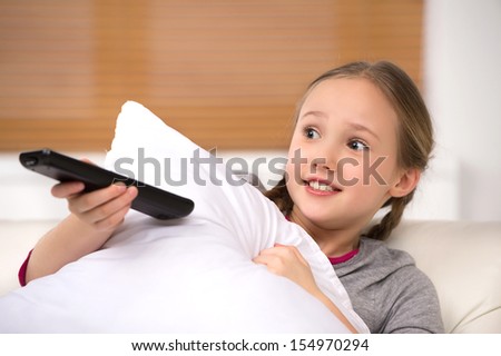 Scared little girl. Cute little girl holding remote control and looking scared