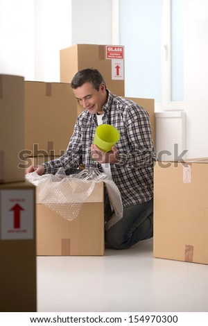 House moving. Cheerful middle-aged man packing the cardboard box and smiling