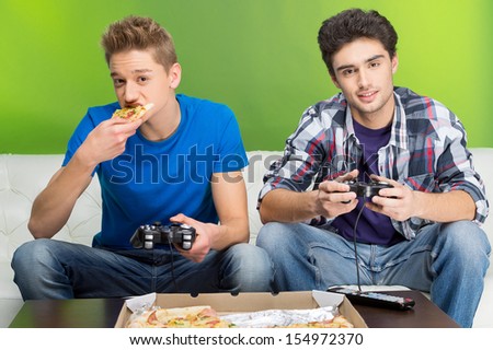 Gamers with joystick. Two young gamers playing video games while sitting on the couch