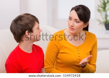 Mother and problem child. Frustrated mother talking to with her son sitting on the couch