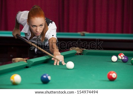 Pool player. Confident young red hair woman playing pool