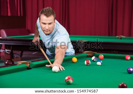 Man playing pool. Confident young man playing pool and looking ahead