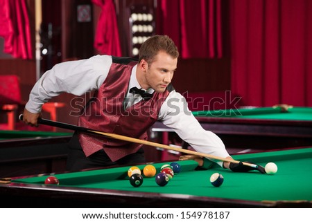 Man playing pool. Confident young man in bow tie playing pool