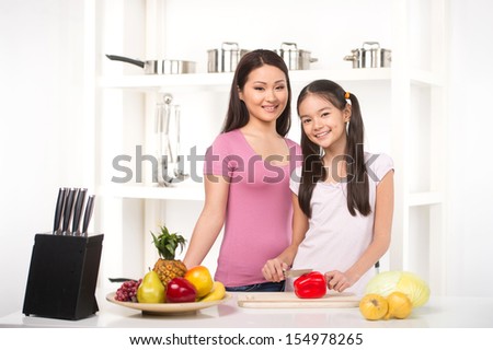 Mother and daughter on the kitchen. Cheerful daughter helping her mother on the kitchen