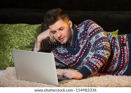 Men surfing web. Handsome young men using computer while lying on the couch