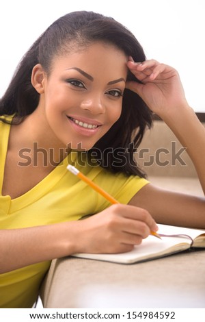 Woman making notes. Beautiful African descent women writing something in her note pad and looking at camera