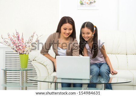 Mother and daughter with laptop. Cheerful daughter and mother working on laptop together
