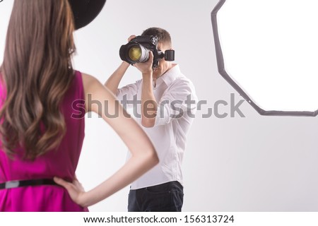 Photographer And Model. Young Man Photographing Fashion Model Holding Hands On Hip