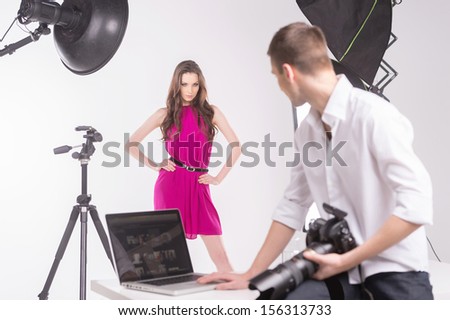 Photographer and model. Photographer holding camera and looking at fashion model
