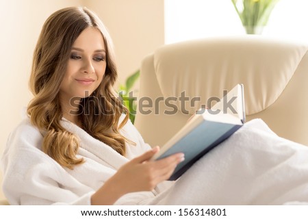 Day off at home. Attractive young woman in bathrobe reading book