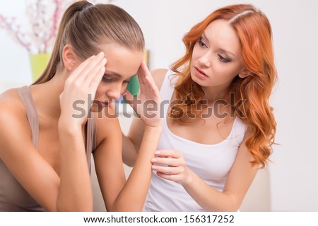 Depressed woman and friend. Beautiful red hair woman sitting close to her depressed friend