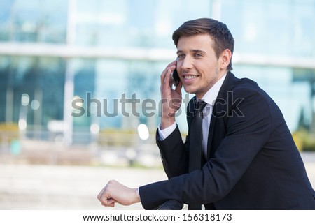 Successful businessman. Cheerful young men in formalwear talking on the mobile phone and smiling