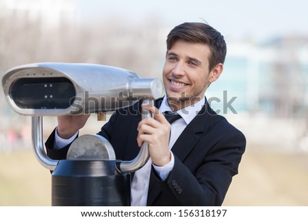 Looking for solutions. Cheerful young men in formalwear looking through stationary binoculars and smiling