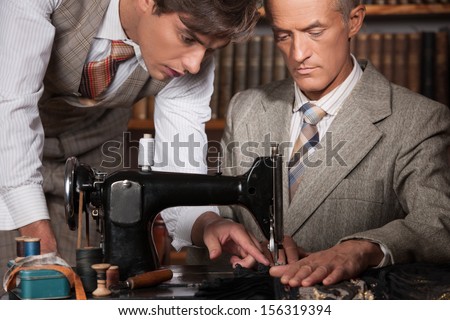 Tailors at work. Two confident tailors working at tailor shop