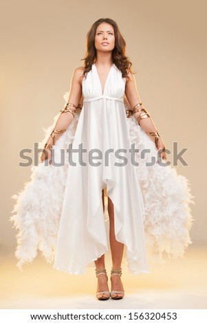 Girl with wings. Full length of beautiful young woman with white wings looking away while standing isolated on colored background