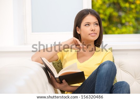 Woman reading. Cheerful young woman sitting on the couch and reading book