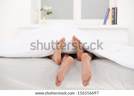 Loving couple in bed. Close-up of human legs stretching out of the bed